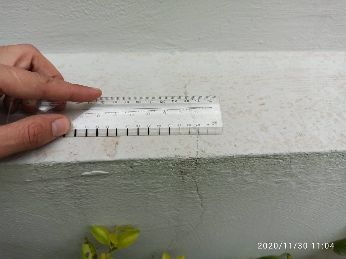 Engenheiro medindo a abertura de uma fissura com fissurômetro durante vistoria cautelar