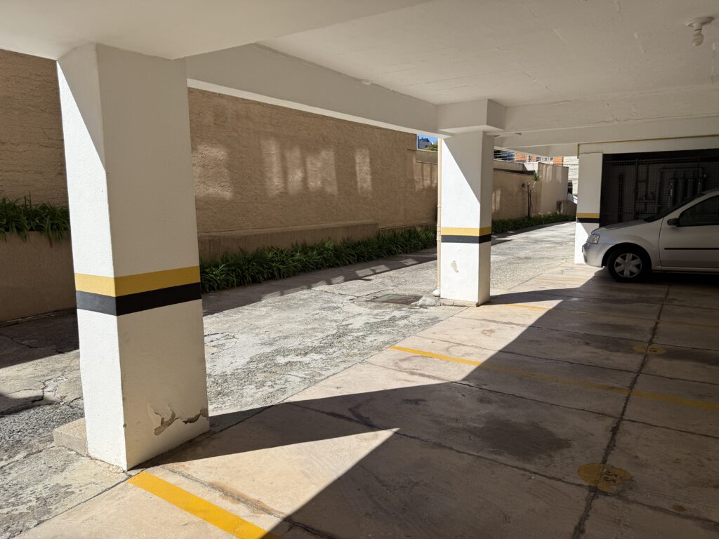 Fissura e umidade na base de pilar de garagem em inspeção predial