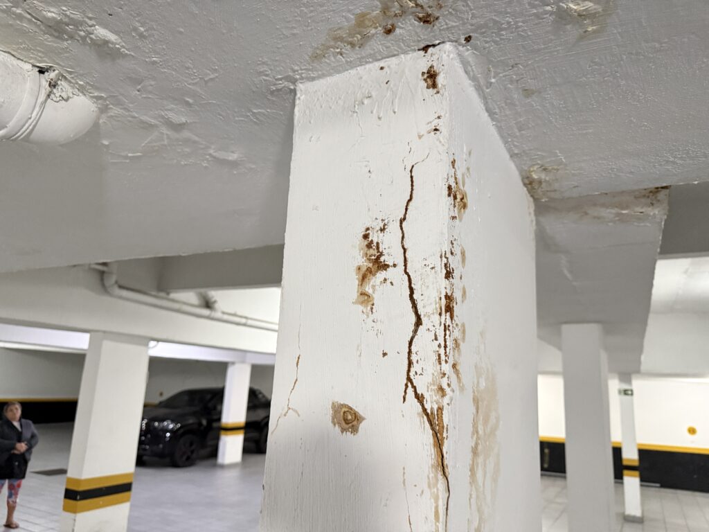 Fissura em pilar e sinais de umidade na laje de garagem registrados em inspeção predial