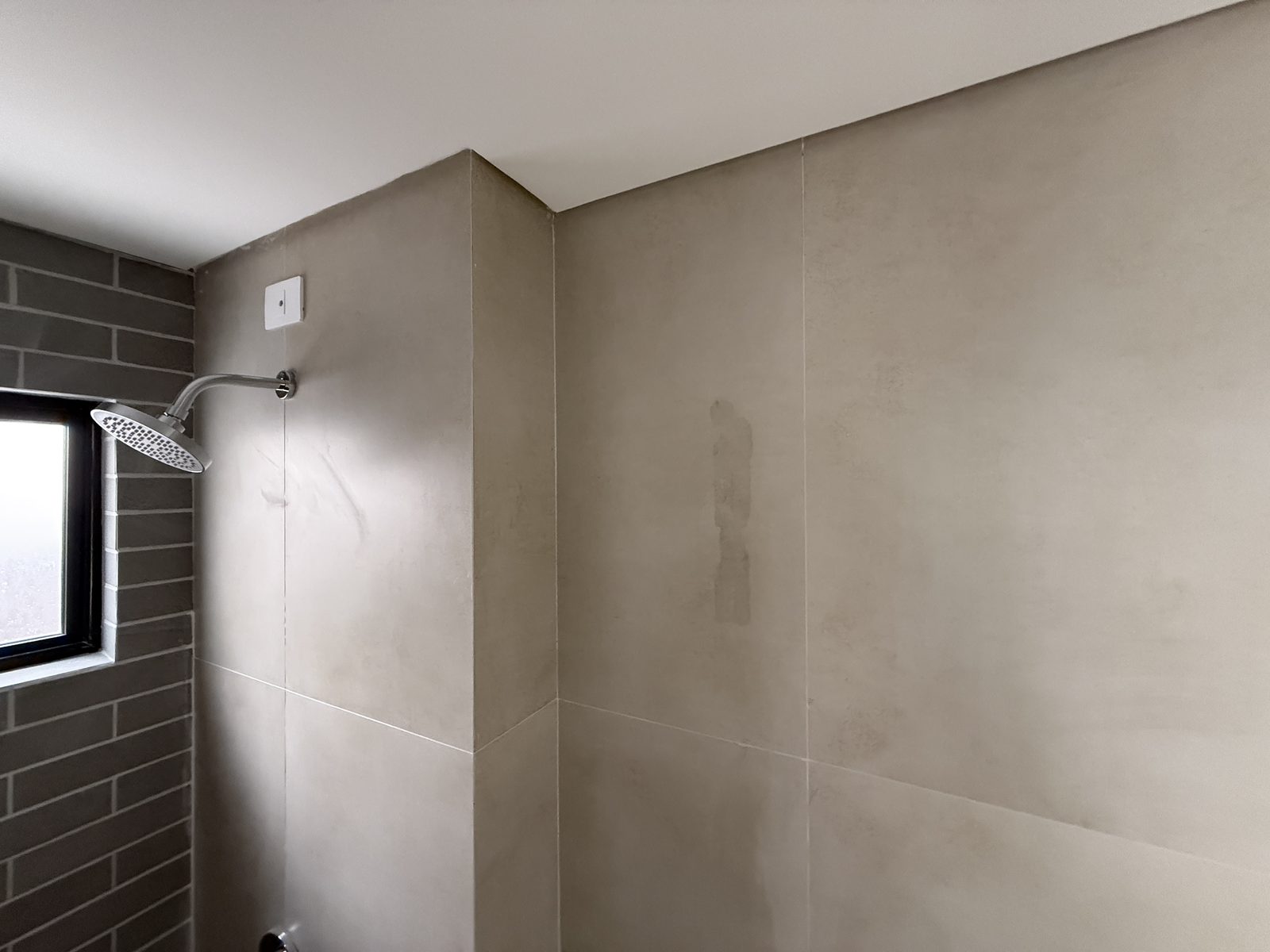 Mancha escura no porcelanato de parede de banheiro em casa nova